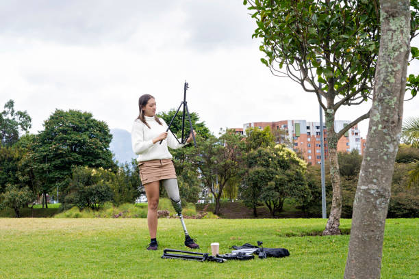 A young influencer with prosthetics sets up a recording crew in a park to create content for social media. The image shows her passion and creativity, demonstrating that there are no barriers to expression. Influencer concept.