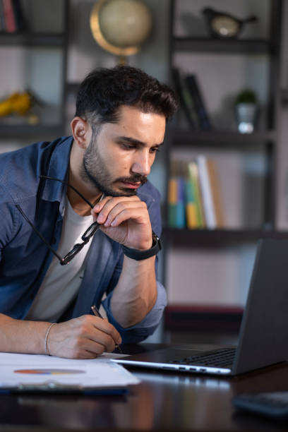 istock Handsome bearded young man working overtime in front of the computer 2178396065