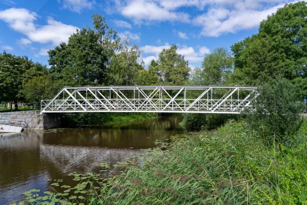 istock White iron bridge over a tranquil river surrounded by lush greenery in Uppsala, Sweden 2178401900