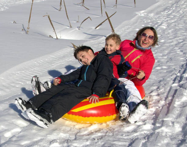 istock Mother with sons on rubber sleds 2178401947