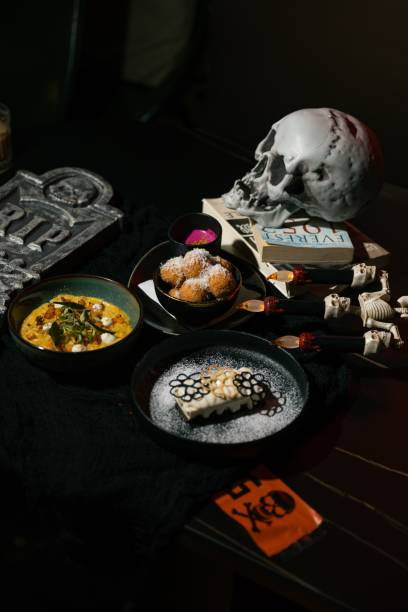 Closeup of Halloween-themed table setting with skull, books, and assorted dishes