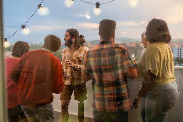istock Diverse group of friends enjoying drinks and conversation on rooftop at sunset 2178406649