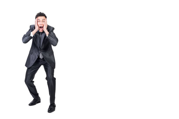 Full body of shocked young businessman with dark hair in formal outfit touching cheeks and screaming against white background