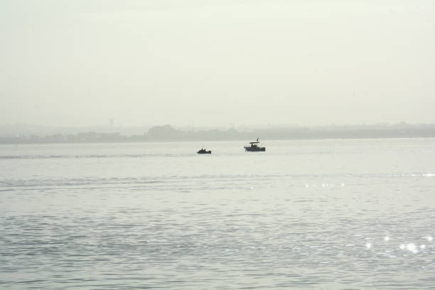 silhouette of a small boat in the middle of the Tagus River