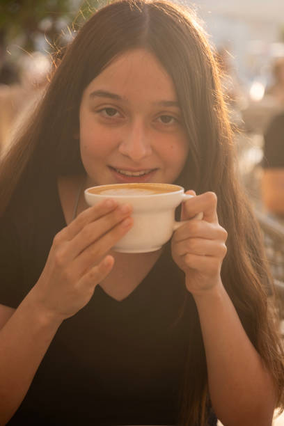 istock Young girl drinking coffee in cafe, smiling and looking at camera. 2178407644