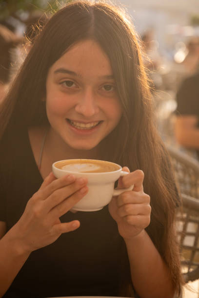 istock Young girl drinking coffee in cafe, smiling and looking at camera. 2178407647