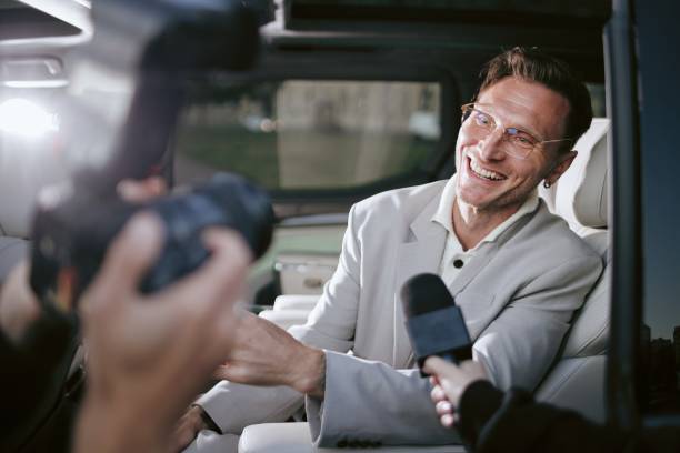 istock Smiling Male Celebrity Speaking with Media Giving Interview while Sitting in Car 2178407974
