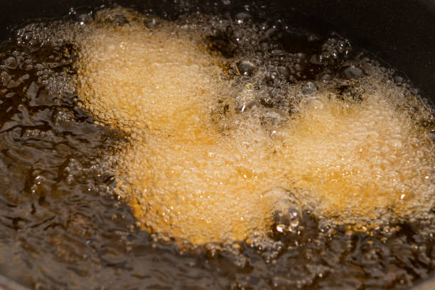 dough fried in boiling oil in a frying pan Boiling oil in a pan with dough chip pan stock pictures, royalty-free photos & images