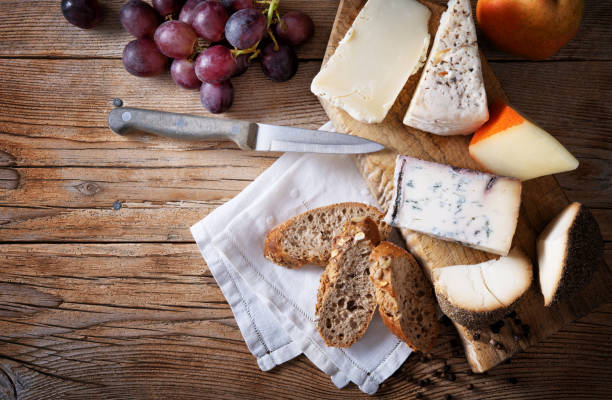 istock Italian cheese: Pecorino rosso, Blu di bufala, Pecorino toscano, Formaggio al pepe. Cheese platter, with bread, grapes and pear on wooden background, top view, space for text. 2178409430