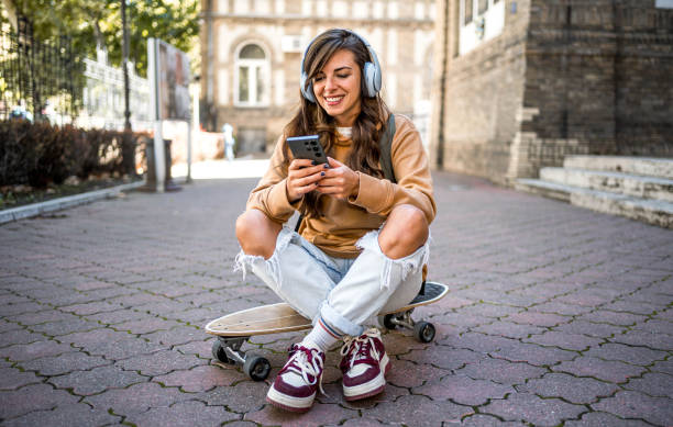 istock Woman sitting on skateboard and using phone 2178412717