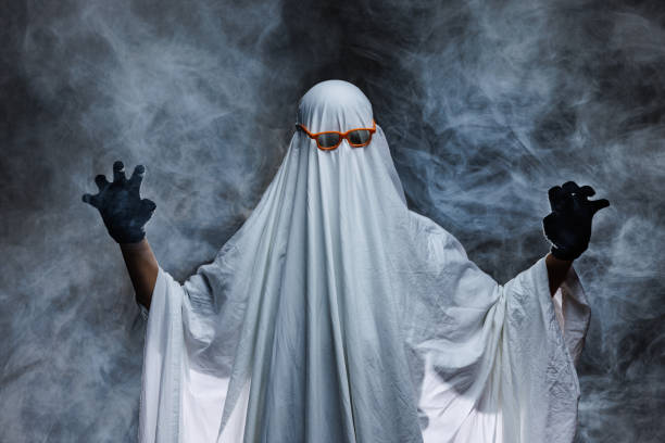 istock man in scary ghost costume in smoke on grey mysterious background in studio. Minimal halloween ghost concept. 2178412925