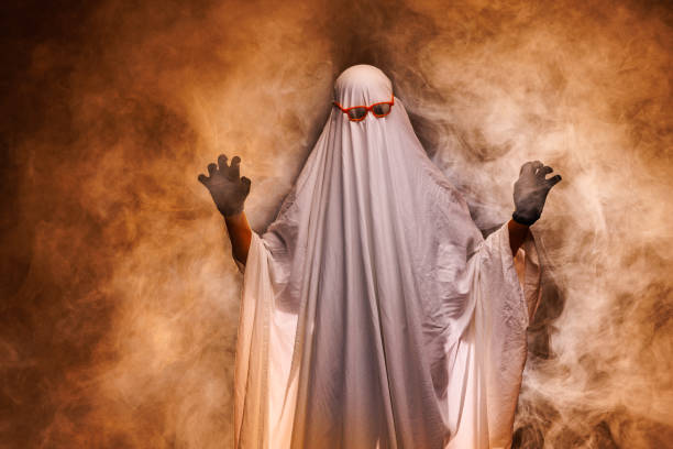 istock man in scary ghost costume in smoke on grey mysterious background in studio. Minimal halloween ghost concept. 2178412928