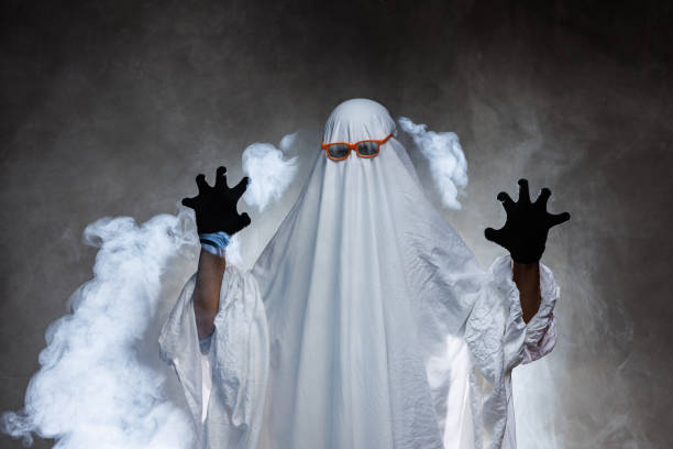 istock man in scary ghost costume in smoke on grey mysterious background in studio. Minimal halloween ghost concept. 2178412998