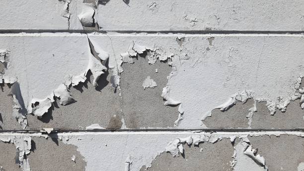 istock White peeling paint on the wall. Weathered rough painted surface with patterns of cracks and peeling. 2178413854