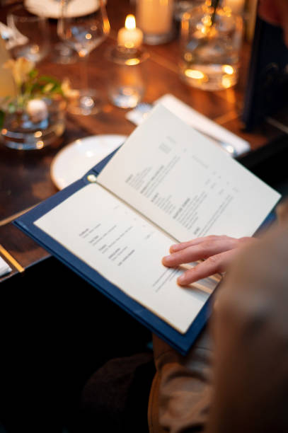 istock Woman reading a menu in a restaurant. Selective focus on the book 2178417186