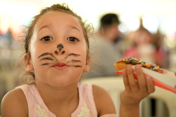 A close-up of young girl eating ice cream while getting a piggyback from her mother. They are at a food festival in Whitley Bay.