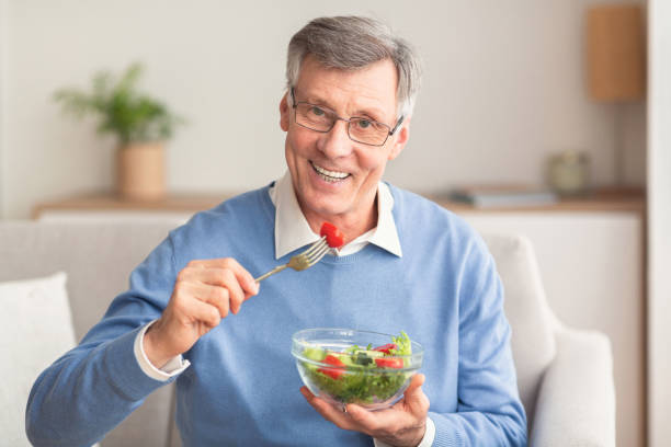 istock Senior Man Eating Vegetable Salad Sitting On Couch At Home 2178422645