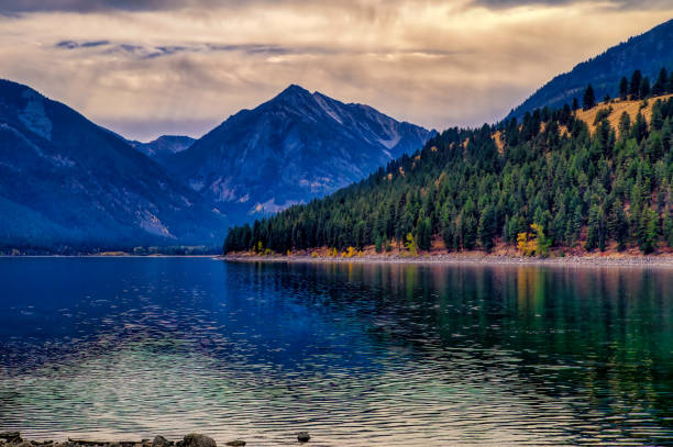 Landscape photography of Rocher du Vent reflecting in Lac de Roselend with a dramatic evening sky, reduced colours, moody atmosphere, vertical