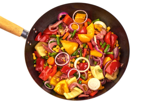 Fried vegetables in a frying pan, isolated on white background.