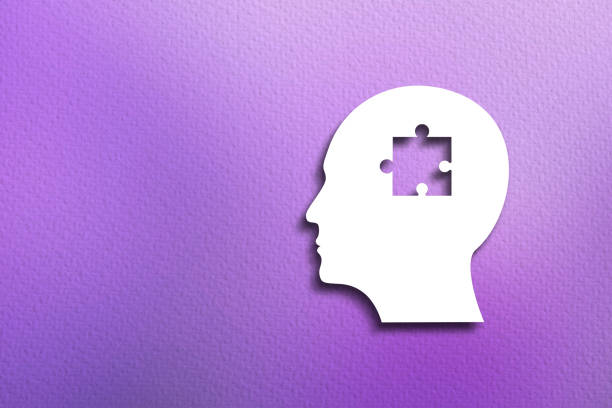 Mental health concept. A missing piece of the human head paper silhouette puzzle on purple background.