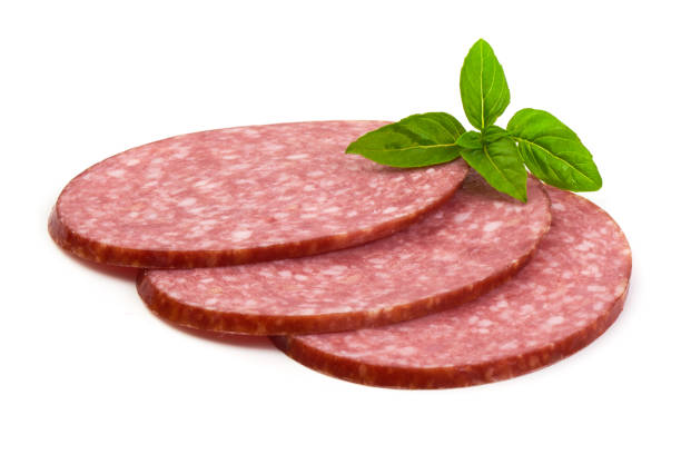 Dry salami sausage slices with basil leaves, isolated on white background
