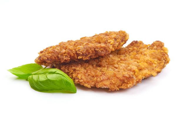 Fried breaded chicken fillet with basil leaves, isolated on a white background. Close-up
