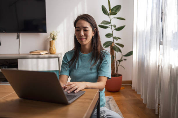 istock Asian woman using laptop at home, focused and working efficiently 2178443298