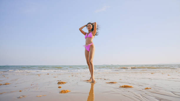 Portrait of athletic girl on seafront. Young sportswoman in pink sportswear and sunglasses doing exercises on concrete wall