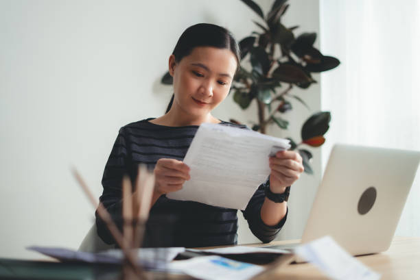 istock Asian woman holding document and using laptop enjoyed with working online sitting at office. 2178457236