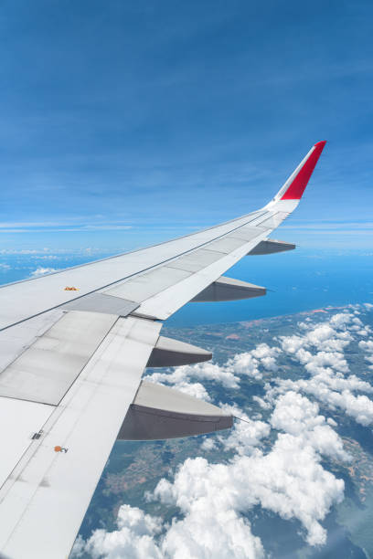 Awesome view of the Earth under the airplane wing. Amazing landscape is visible through airplane window. Traveling by plane. Flying in the sky among clouds.