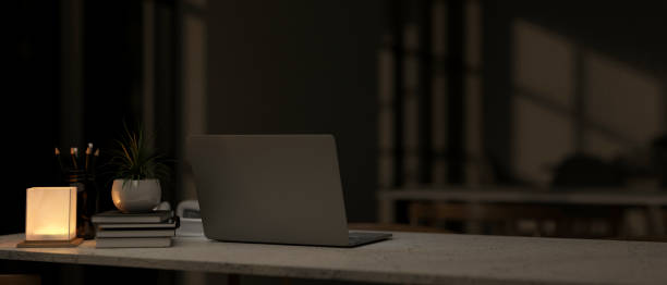 istock A back view of a laptop on a table in a modern dark room at nighttime, illuminated by a table lamp. 2178460422