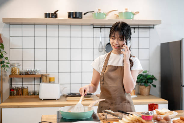 istock A charming Asian woman is talking on the phone while cooking in the kitchen. 2178461211