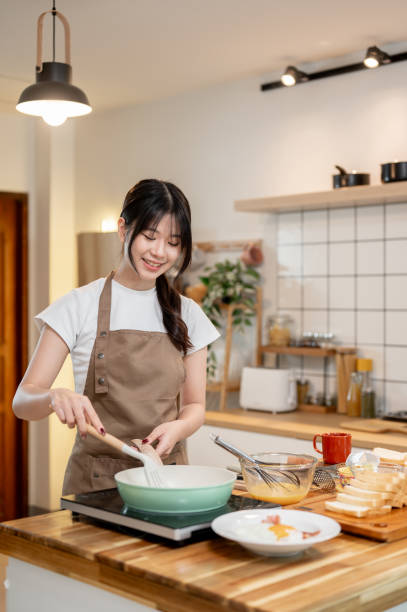 istock A happy Asian woman is cooking in the kitchen, making scrambled egg in a pan for her breakfast. 2178461239