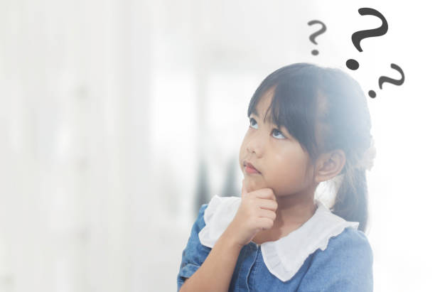 istock Kid girl Touching his chin with a dubious expression and looking up as if thinking with graphic question marks around her with copyspace. 2178463129