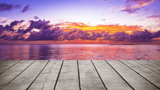 Empty wooden table top with tropical ocean sunset with dramatic sky and clouds background
