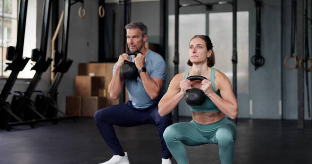istock Fitness Couple In Gym. Training With Kettlebell 2178465110