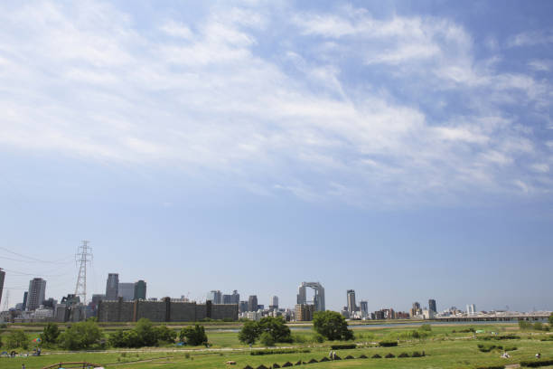 The buildings of the big city of Osaka can be seen from a park on both sides of the Yodo River that flows into Osaka Bay. It is an interesting image of two contrasting landscapes with a green square full of nature.
