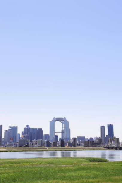 The buildings of the big city of Osaka can be seen from a park on both sides of the Yodo River that flows into Osaka Bay. It is an interesting image of two contrasting landscapes with a green square full of nature.