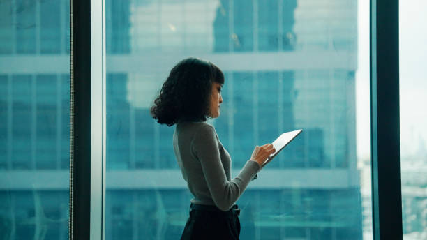 istock Young Asian woman looking for inspiration outside the window while working on her digital tablet. 2178469110