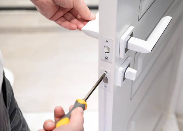 istock Locksmith using a screwdriver to install or repair a door lock, focusing on the precise work of securing the lock mechanism 2178471577