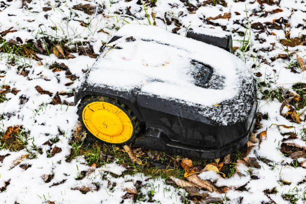 Robotic Lawn Mower. Robotic Lawn Mower on the grass covered with fist snow. Automatic robot lawnmower, first snow day.