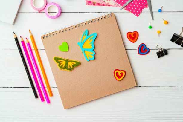 Crafting inspiration with colored pencils, decorative tape, and playful shapes on a rustic wooden surface close up