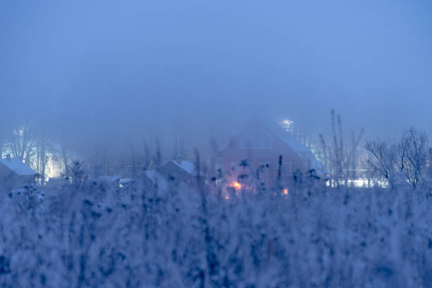 Digitally generated quiet winter evening, where snowflakes are drifting down in a dense flurry, blanketing the ground while a warmly lit cabin nestles in the backdrop of a dark pine forest. A figure, possibly engaged Nordic walking, stands in the foreground, using a powerful flashlight that it's glowing light source pierces through the twilight misty fog.\n\nThe scene was created in Autodesk® 3ds Max 2024 with V-Ray 6 and rendered with photorealistic shaders and lighting in Chaos® Vantage with some post-production added.