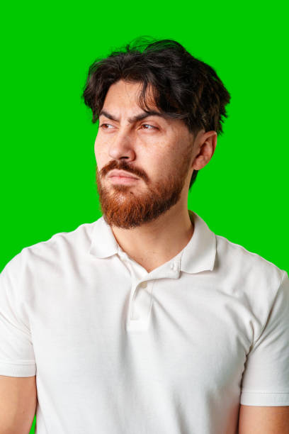 istock A man with a serious expression stands with crossed arms against a vibrant green background 2178471840