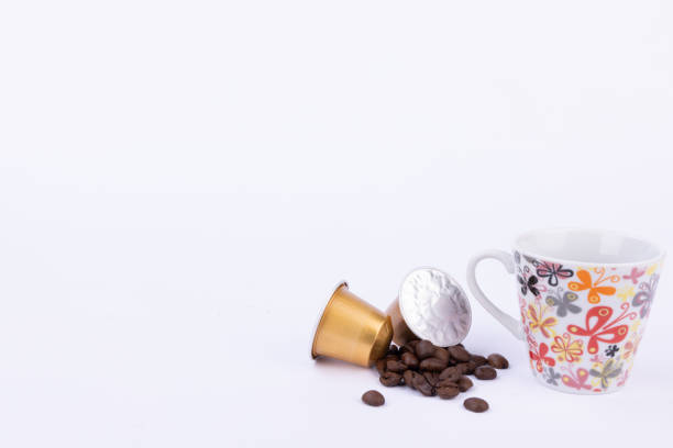 istock Golden Coffee Capsules and Beans with Coffee Cup on White Background 2178472449