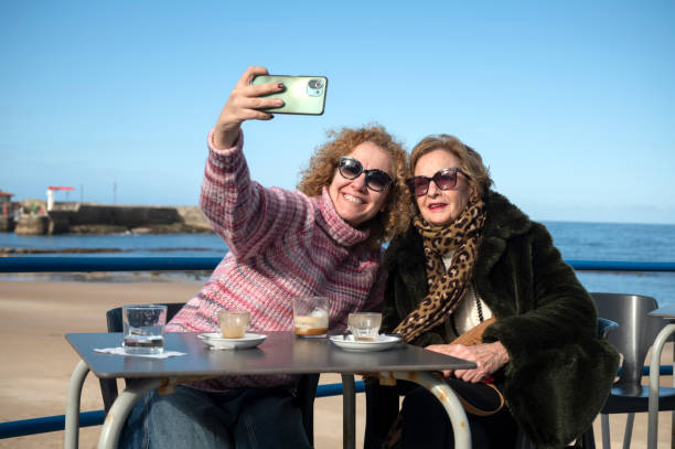 istock Mother and daughter taking a selfie while enjoying coffee by the beach 2178474408
