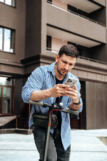 istock Young man enjoying a sunny day while riding an electric scooter through a modern urban setting 2178474617