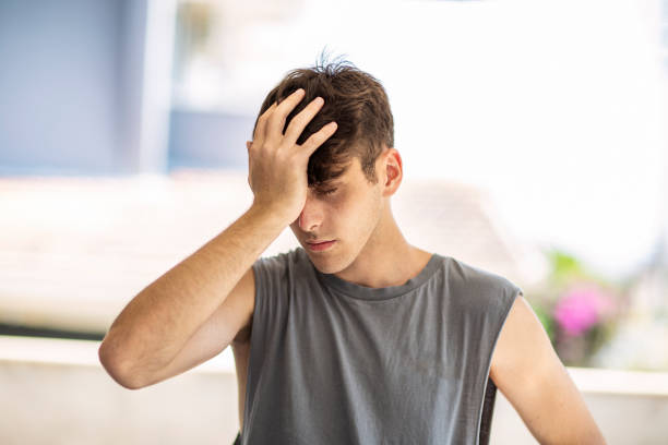istock Young handsome man standing with his hand placed on his forehead, coverig his eyes as if he's upset or frustrated 2178477490