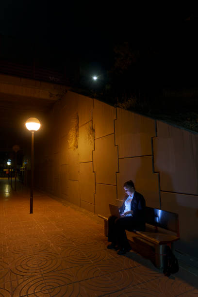 istock Woman Working on Laptop While Waiting for Train at Nighttime Station 2178477684