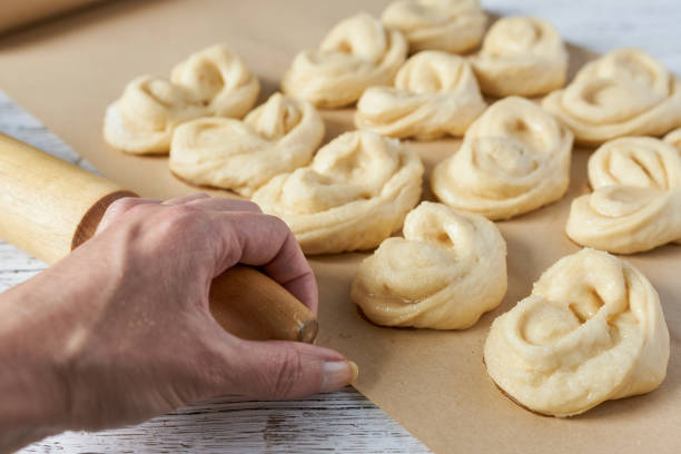 istock A woman's hand holding a rolling pin against a background of dough buns on a baking sheet. Cooking buns. 2178477685